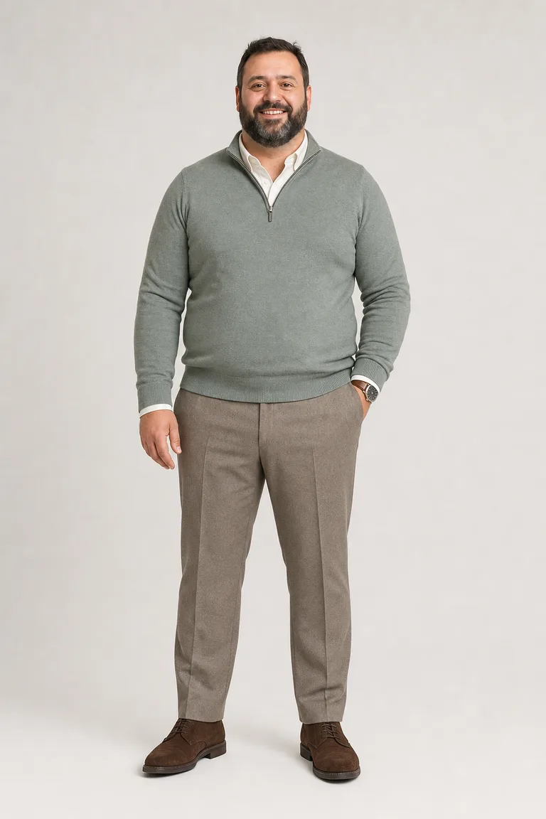 Big and tall man with a dark beard in a sage quarter-zip over an ivory oxford shirt, taupe trousers and chocolate suede derbies.