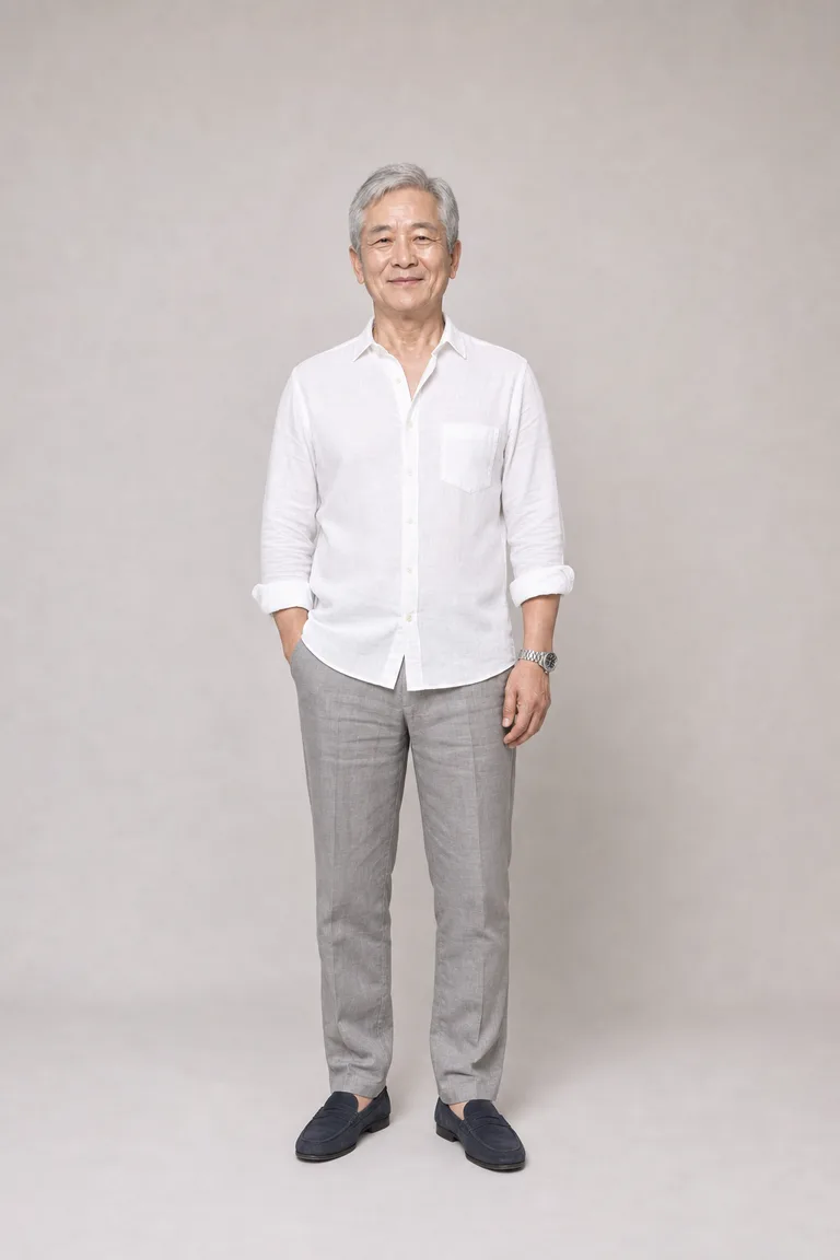 An East Asian man in his sixties in a white linen shirt with rolled sleeves, gray linen trousers and navy suede loafers.